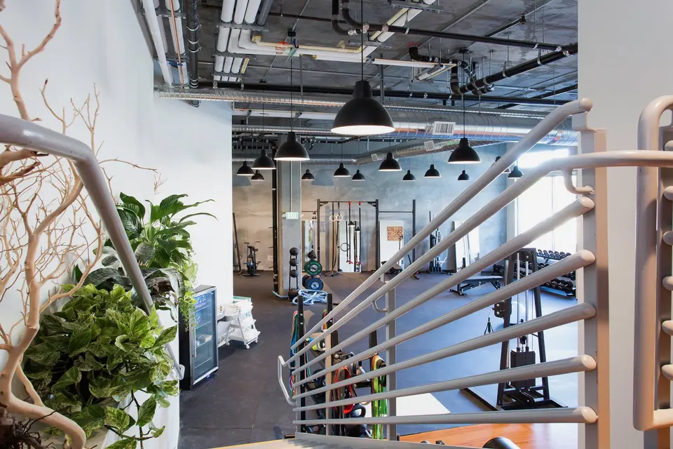 Training floor with racks and pendant lights seen from the stairs at Custom Fit Market Street