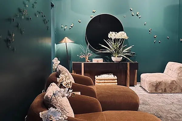 Relaxation lounge at EvolvE with a curved brown sofa, plush chairs and butterfly decals on a deep teal wall