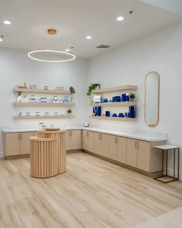 Reception area at Highland Longevity with a round wood desk, floating shelves of products and a ring pendant light