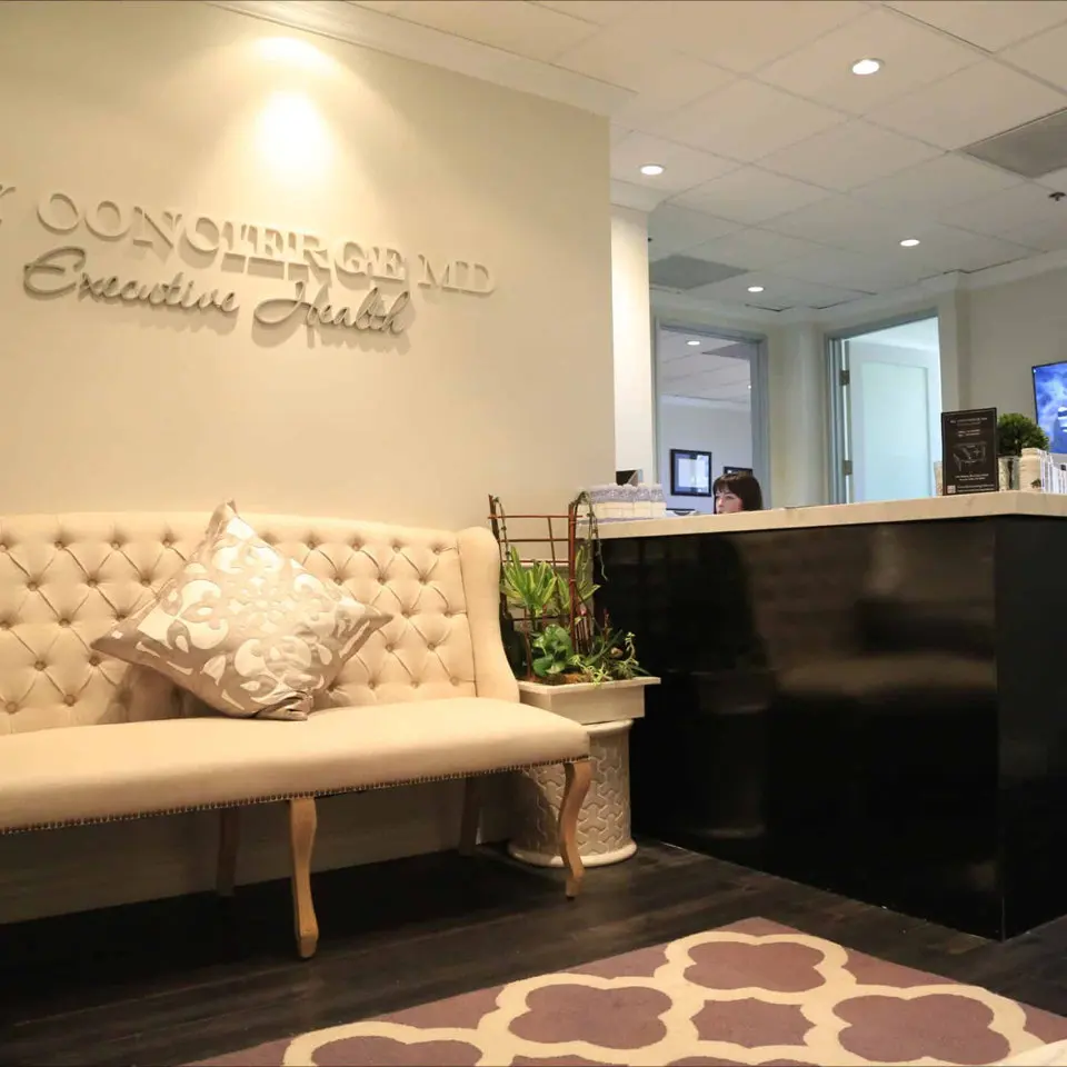 Reception and tufted bench under the Concierge MD Executive Health sign